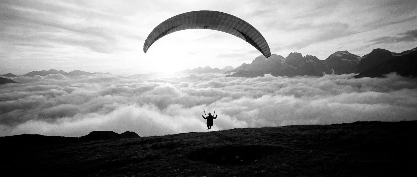 Paraglider launching off a high ridge above a sea of cloud, representing AI and search visibility services