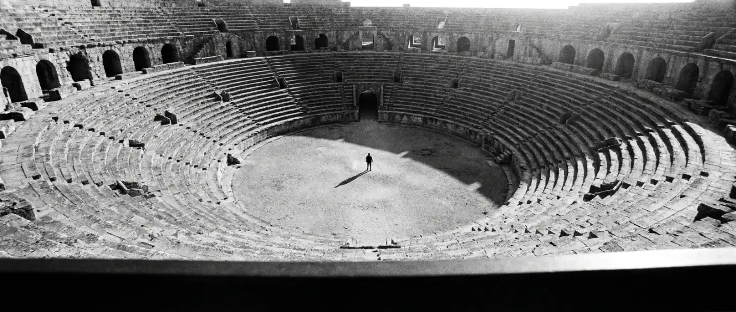 Lone figure at the centre of a vast empty stone amphitheatre, representing answer engine optimisation