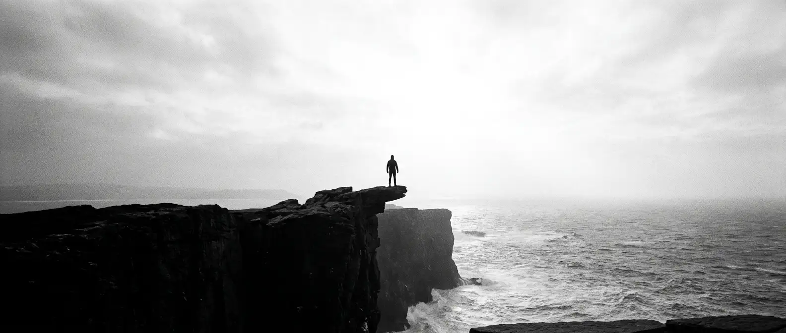 Lone figure on a narrow rock plinth high above a vast ocean, representing brand authority and digital presence