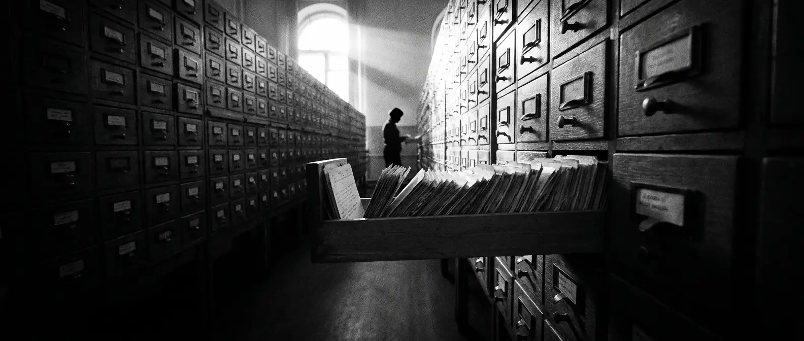 Archive aisle of card catalogue drawers with one drawer pulled open, representing citation and source development