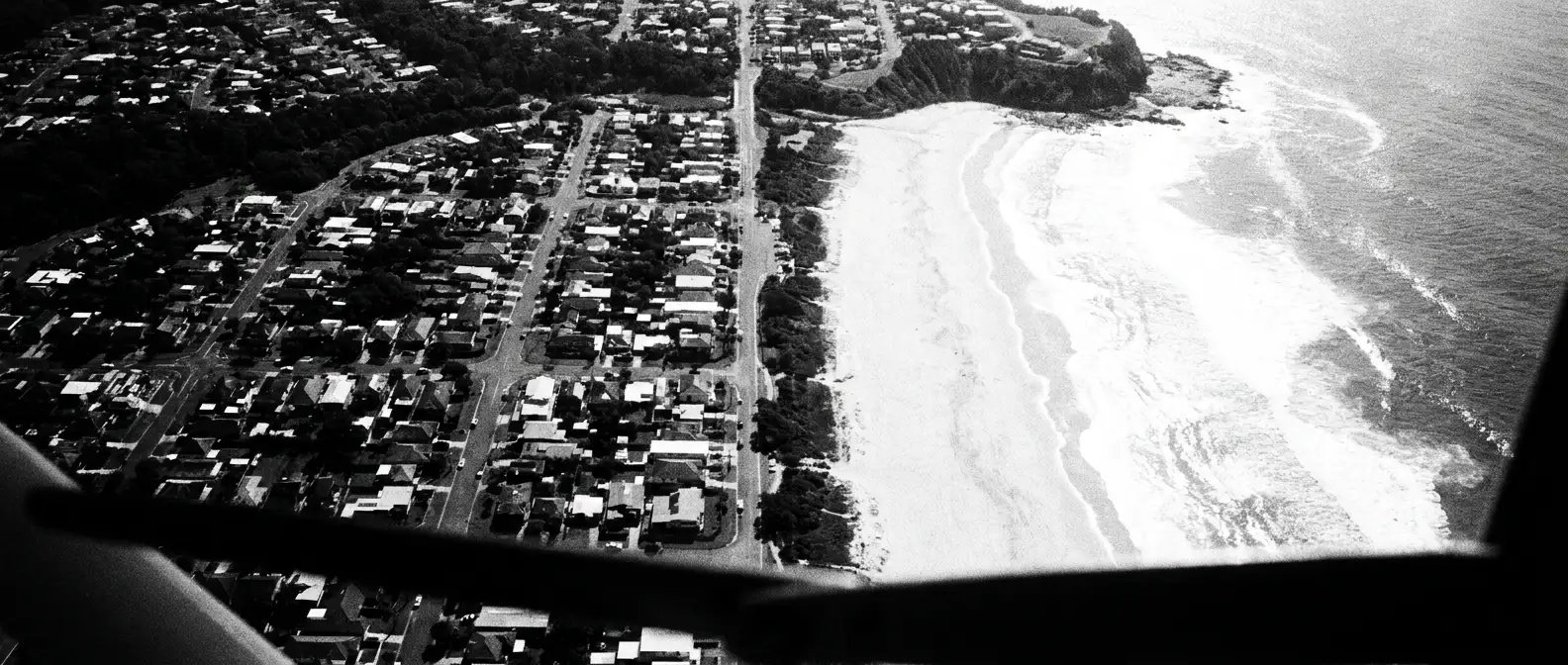Aerial view of an Australian coastal suburb street grid meeting the beach, representing local AI and search visibility
